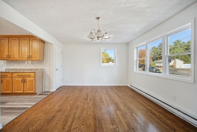 unfurnished dining area with light hardwood / wood-style flooring, a textured ceiling, a chandelier, and a baseboard radiator