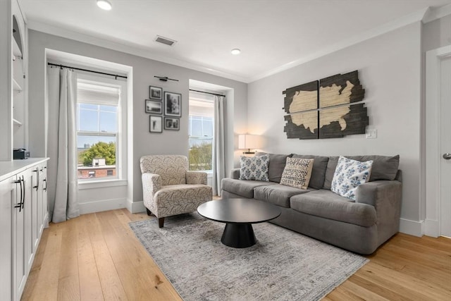 living room with crown molding, light wood-style flooring, and a healthy amount of sunlight