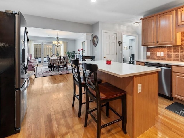 kitchen featuring appliances with stainless steel finishes, brown cabinetry, light countertops, and a kitchen island