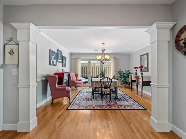 dining area featuring ornate columns, an inviting chandelier, ornamental molding, light wood-type flooring, and baseboards