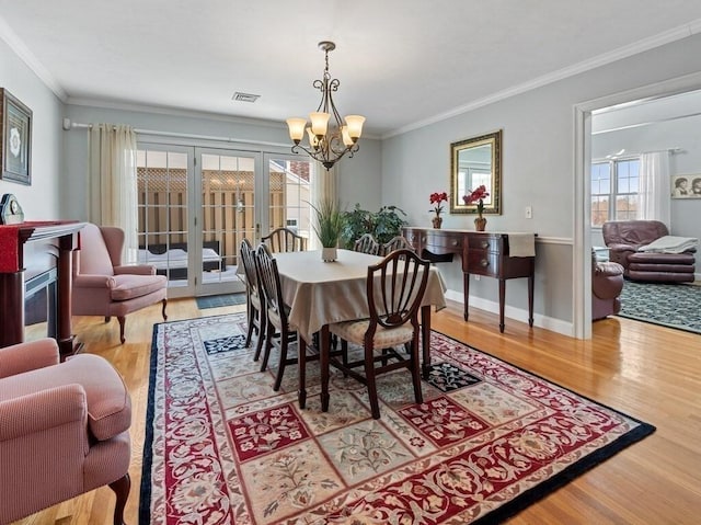 dining room with light wood-style floors, baseboards, ornamental molding, and an inviting chandelier