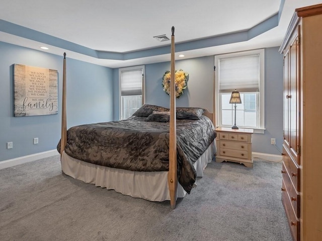 bedroom featuring light carpet, a raised ceiling, visible vents, and baseboards