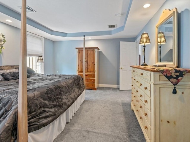 carpeted bedroom featuring baseboards, visible vents, a tray ceiling, and recessed lighting