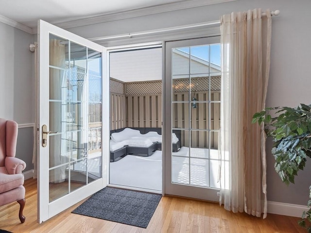 doorway to outside with baseboards, french doors, light wood-type flooring, and crown molding