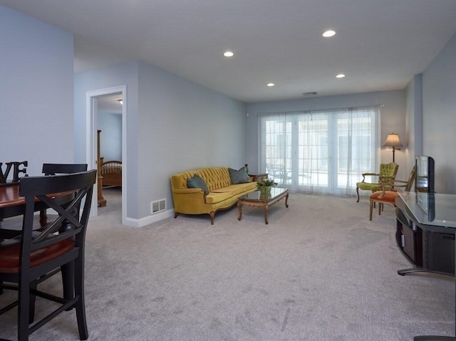 living room with recessed lighting, visible vents, and light colored carpet