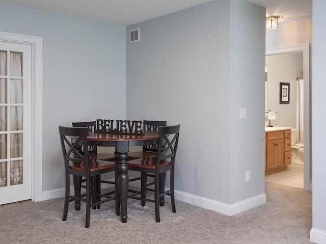 dining area with light colored carpet, visible vents, and baseboards