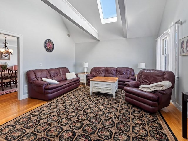 living room featuring vaulted ceiling with skylight, visible vents, a chandelier, and wood finished floors