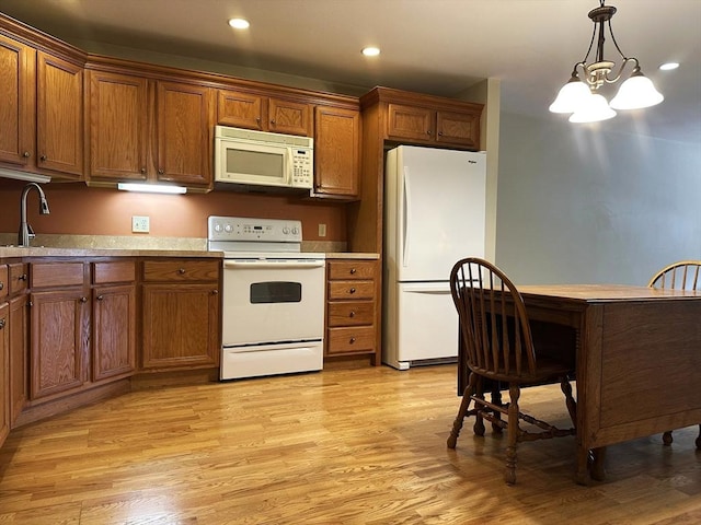 kitchen with light wood-type flooring, white appliances, light countertops, and decorative light fixtures