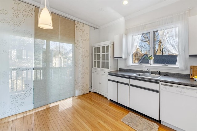 kitchen with white dishwasher, white cabinets, crown molding, sink, and hanging light fixtures