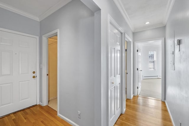 hallway with light hardwood / wood-style floors, ornamental molding, and a baseboard radiator