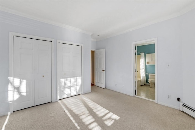 unfurnished bedroom with ensuite bath, multiple closets, baseboard heating, light colored carpet, and ornamental molding