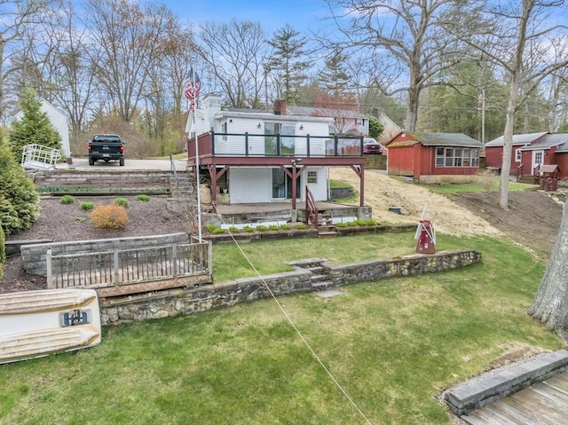rear view of house with a wooden deck, a shed, stairway, an outbuilding, and a lawn