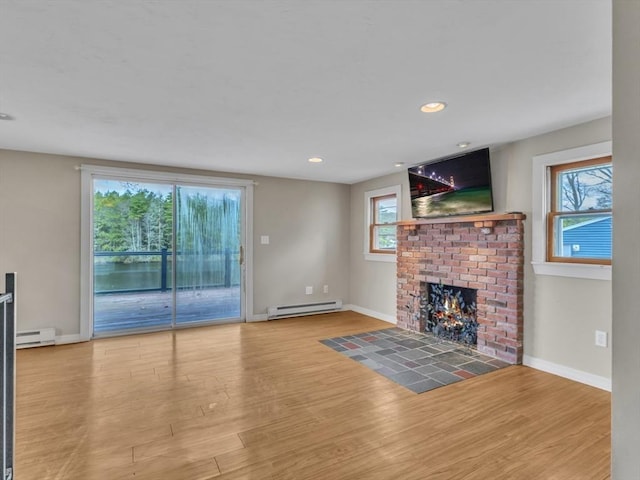 unfurnished living room with baseboards, a baseboard heating unit, and a healthy amount of sunlight