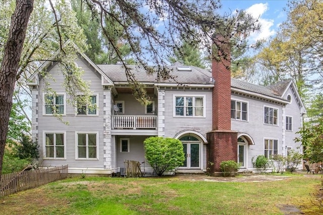 rear view of property with a balcony, a chimney, and a shingled roof