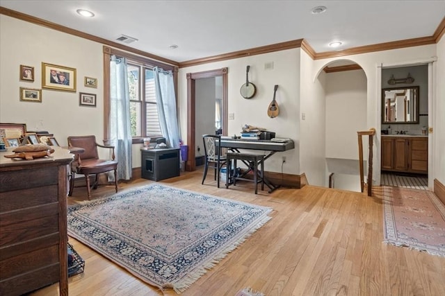 sitting room with light wood-style flooring, ornamental molding, baseboards, and a desk