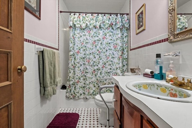 bathroom featuring tile walls, toilet, a wainscoted wall, vanity, and shower / tub combo
