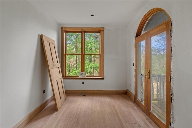 doorway featuring french doors, plenty of natural light, light wood finished floors, and baseboards