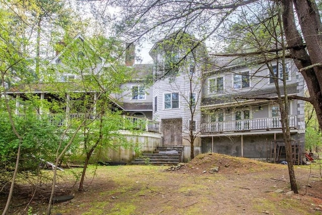 rear view of property with a deck, stairs, and a chimney