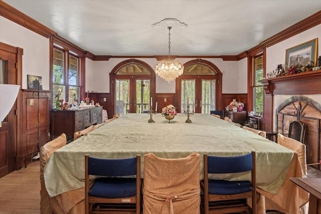 dining room featuring french doors, a wainscoted wall, healthy amount of natural light, crown molding, and wood finished floors