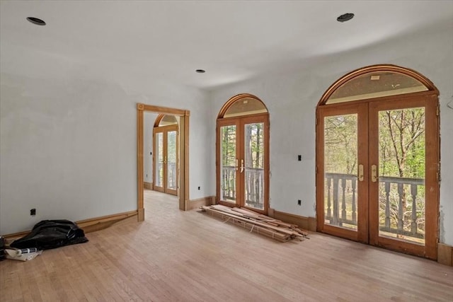spare room featuring french doors, wood finished floors, and baseboards