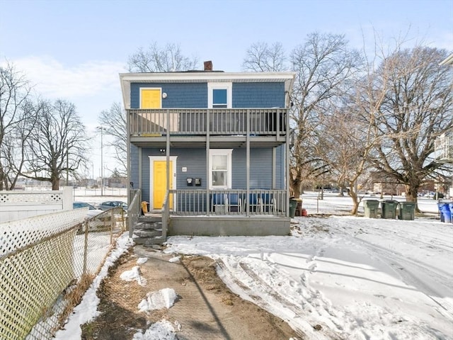 snow covered property featuring a balcony and covered porch