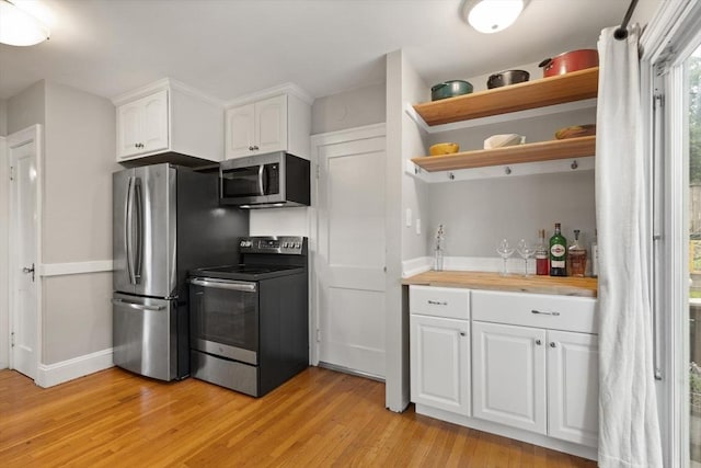 61 Fiske Ave, Waltham, MA 02453 - kitchen with stainless steel appliances, light wood finished floors, open shelves, and white cabinetry