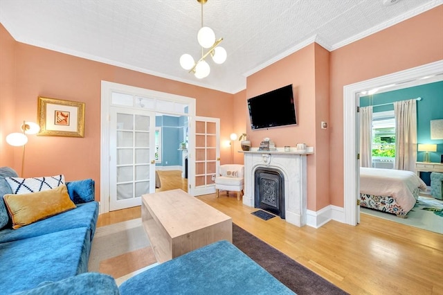 17 Teel St Unit 1, Arlington, MA 02474 - living area featuring wood finished floors, a fireplace with flush hearth, ornamental molding, french doors, and a chandelier