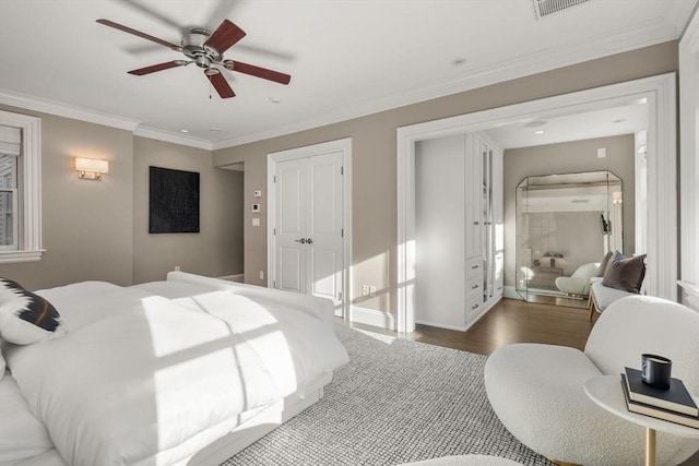 bedroom with ornamental molding, wood-type flooring, ceiling fan, and a closet