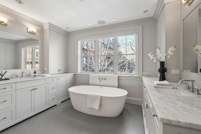 bathroom featuring crown molding, a tub to relax in, a healthy amount of sunlight, and vanity