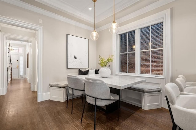 dining area with breakfast area, ornamental molding, a tray ceiling, and dark wood-type flooring