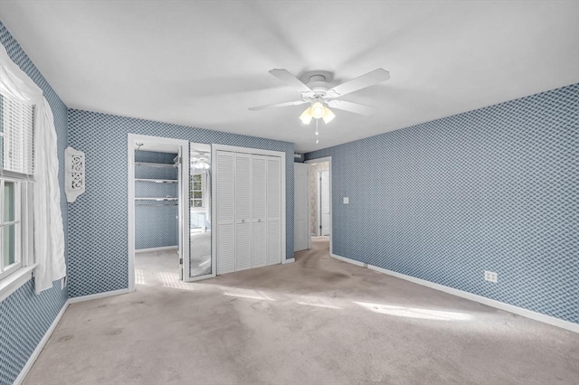 unfurnished bedroom with light colored carpet, ceiling fan, and multiple closets