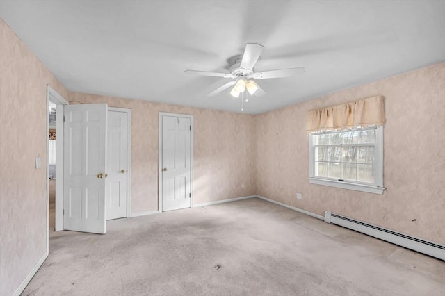 unfurnished bedroom featuring baseboard heating, multiple closets, ceiling fan, and light carpet