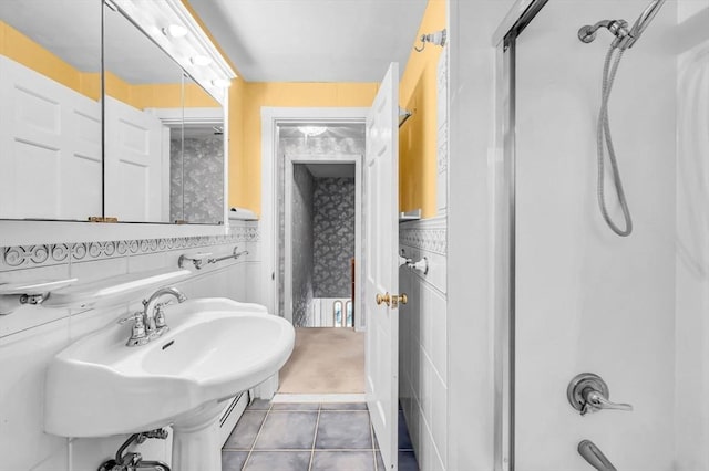 bathroom featuring tile patterned flooring, tub / shower combination, tile walls, and sink