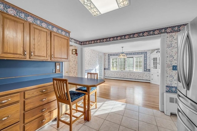 kitchen with stainless steel fridge, light tile patterned floors, a baseboard radiator, and decorative light fixtures