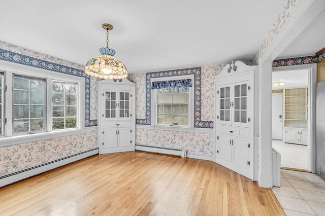 unfurnished dining area featuring a baseboard radiator and light hardwood / wood-style floors