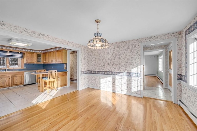 kitchen with pendant lighting, stainless steel dishwasher, light wood-type flooring, baseboard heating, and plenty of natural light