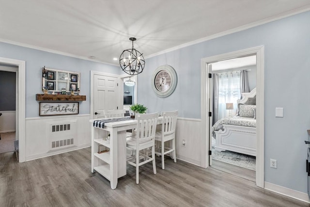 dining space with wainscoting, visible vents, crown molding, and wood finished floors