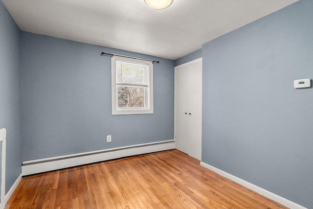 spare room featuring a baseboard radiator, wood-type flooring, and baseboards