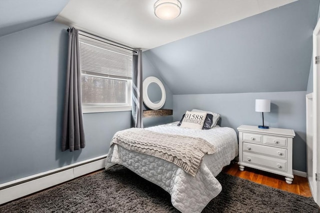 bedroom with a baseboard heating unit, vaulted ceiling, dark wood finished floors, and baseboards