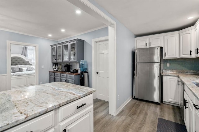 kitchen with stainless steel appliances, light stone counters, light wood-type flooring, and glass insert cabinets