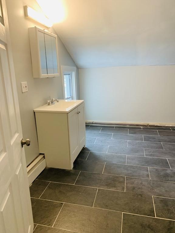 bathroom with a baseboard heating unit, vaulted ceiling, and vanity