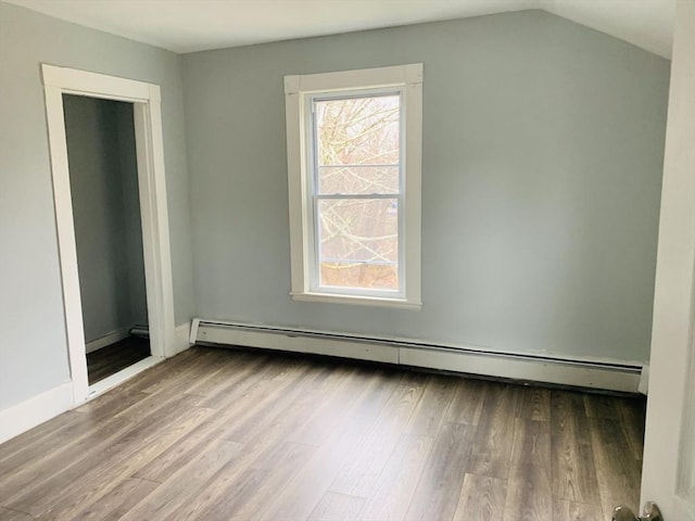 unfurnished room with vaulted ceiling, baseboard heating, and hardwood / wood-style flooring