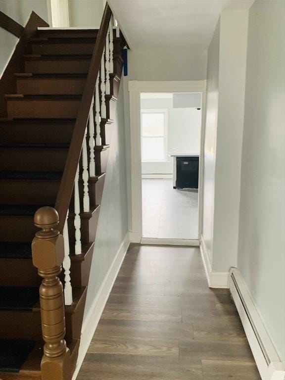 stairs with wood-type flooring and a baseboard radiator