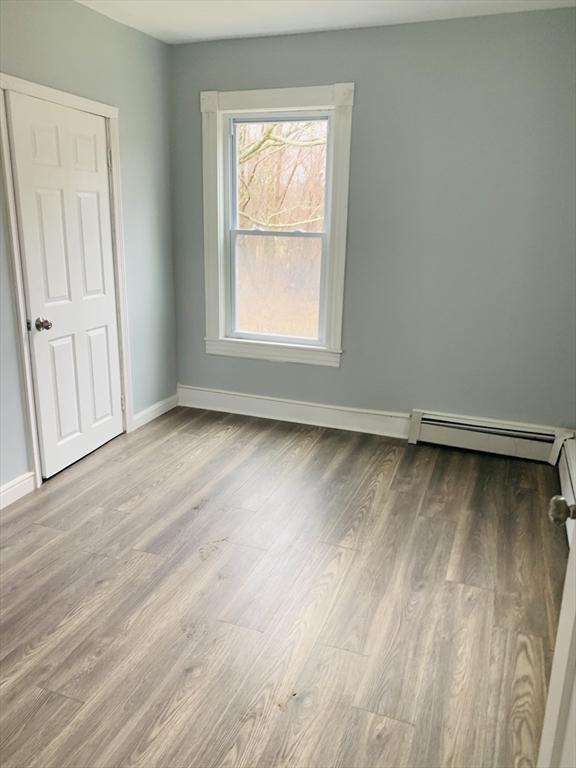 empty room featuring a baseboard heating unit and light hardwood / wood-style flooring