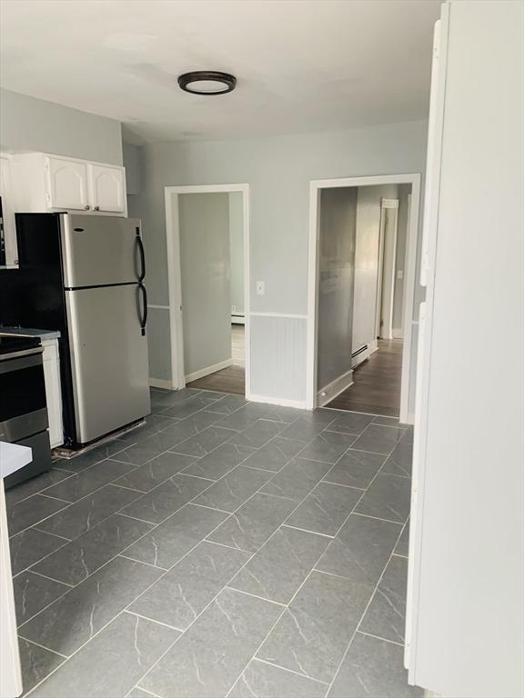 kitchen with white cabinets, appliances with stainless steel finishes, and baseboard heating