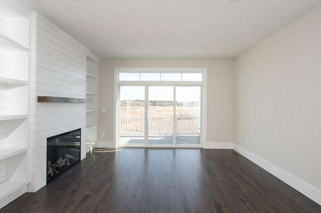 unfurnished living room with dark hardwood / wood-style floors, a large fireplace, and built in features