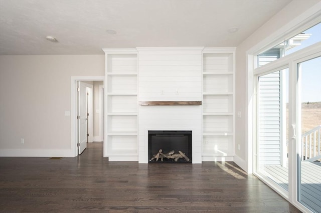 unfurnished living room featuring dark hardwood / wood-style floors, built in features, and a fireplace