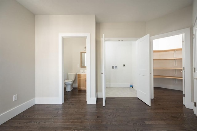 unfurnished bedroom with ensuite bathroom, dark hardwood / wood-style flooring, a walk in closet, and a closet