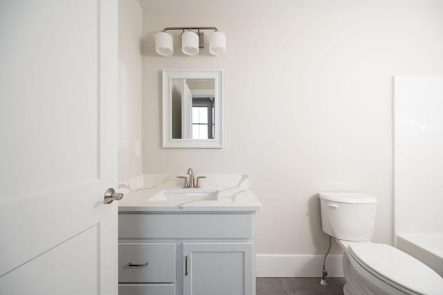 bathroom featuring tile patterned flooring, a bath, vanity, and toilet