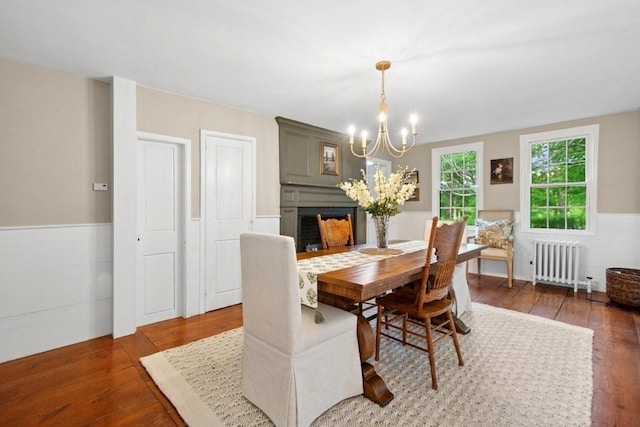 38 S St, Grafton, MA 01519 - dining area with radiator heating unit, a chandelier, wood finished floors, a wainscoted wall, and a fireplace